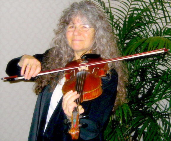 Denya fiddling in front of a fern